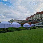 Białe namioty plenerowe na trawniku Ogrodów Zamkowych przy Zamku Królewskim w Warszawie – wynajem na event