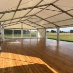 Biały namiot weselny z drewnianą podłogą i przeszklonymi ścianami w plenerze, wynajem pod Krakowem