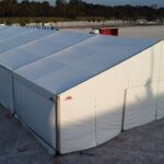 Duża biała hala namiotowa z pełnym opłotowaniem na otwartym terenie o zmierzchu – wynajem namiotu eventowego